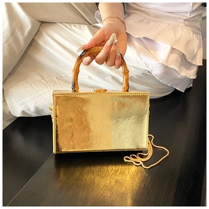 Detail of gold metallic box bag with vintage bamboo handle and gold chain strap