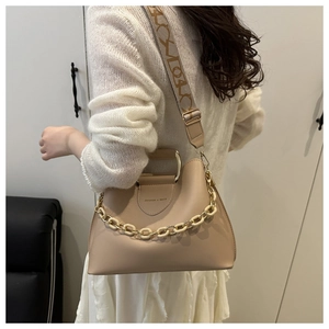 Detail of beige crossbody bag featuring a metal handle and wide printed shoulder strap