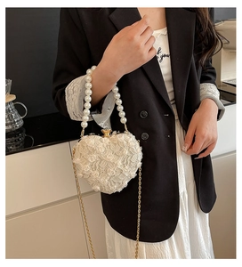 Detailed view of elegant white lace heart-shaped evening bag with pearl handle and gold chain