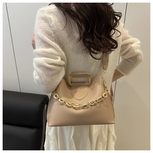 Detail view of beige crossbody bag with acrylic chain decoration and gold hardware