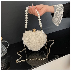 Detail of heart-shaped evening bag with white lace flowers and pearl handle