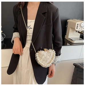 Close-up of heart-shaped lace evening bag with pearl trim and gold chain on model