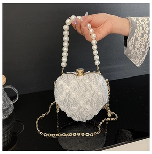 Detail of heart-shaped lace bag with pearl handle, floral embroidery and gold metal clasp
