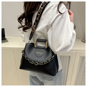Detail of black leather bucket bag with chunky gold chain and geometric strap