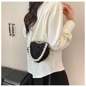 Detail of heart-shaped lace evening bag with pearl handle and rhinestone closure