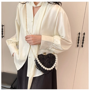 Macro shot of heart-shaped lace bag with 3D rose details and pearl handle