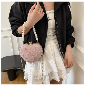 Close-up of pink lace heart bag with pearl handle and floral embroidery on a model