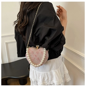 Close-up of pink lace heart-shaped bag with pearl handle and rose embroidery detail