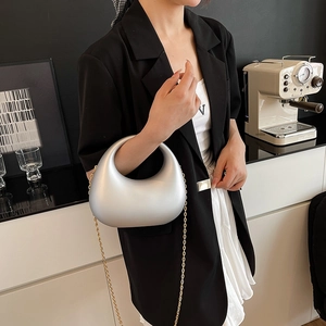 Silver crescent acrylic handbag with golden chain strap for women in a modern setting
