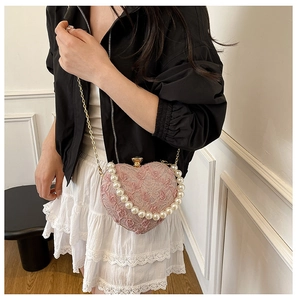 Detail of pink heart-shaped lace bag with large pearl handle and gold chain strap