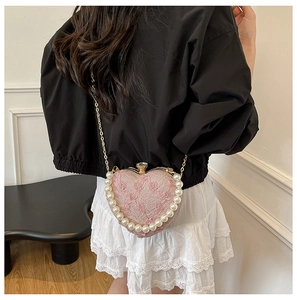 Detail of pink heart-shaped lace evening bag with faux pearl trim and rhinestone clasp