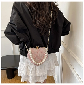 Pink heart-shaped lace evening bag with pearl handle and metal chain on a model