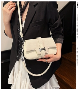 Close-up of cream leather shoulder bag with iconic silver H buckle on model in chic blazer
