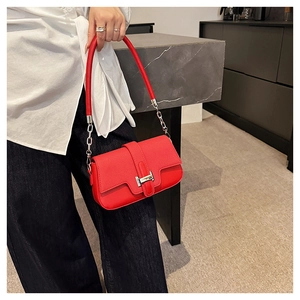 Detail view of red grainy leather handbag featuring a signature golden H-shaped buckle clasp