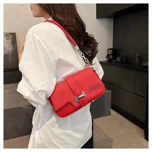 Detailed view of the red lychee pattern leather texture and silver H-shaped buckle on the bag