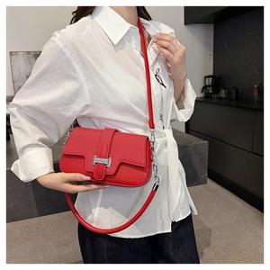Detailed view of red leather crossbody bag with silver H-buckle and metal chain strap