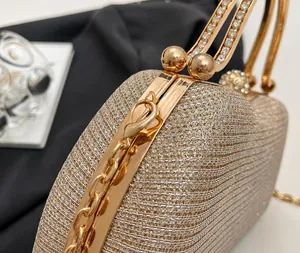 Detailed close-up of golden evening clutch handle with sparkling rhinestone inlay and hardware