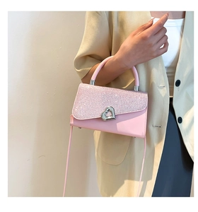 Detail of pink leather handbag with glittery flap and heart-shaped metal clasp
