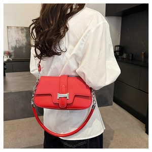 Close-up of bright red pebbled leather shoulder bag with silver H-shaped metal buckle