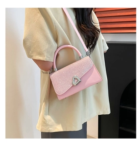 Detail of pink glitter clutch bag with heart lock on beige dress background