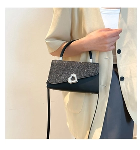 Detail of black glitter flap shoulder bag with silver heart buckle and top handle strap