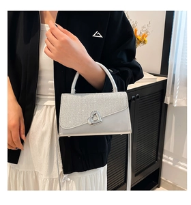 Detail of silver crossbody bag with sparkling heart-shaped metal twist lock closure