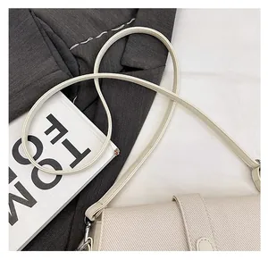Detail of cream crossbody bag showing twill texture and slim faux leather strap