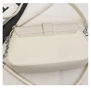 Detail view of cream leather shoulder bag with beige woven fabric flap and metal chain