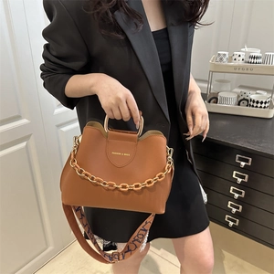 Minimalist brown leather crossbody bag with metal handles and chunky chain detail