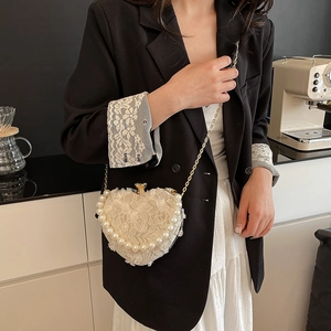 Lace heart-shaped evening bag with pearl trim and gold chain shown on a model