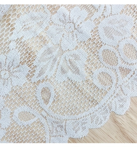 Detailed macro view of white floral lace fabric with delicate scalloped wavy edges