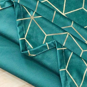 Dark green velvet tablecloth with gold geometric patterns on a wooden background