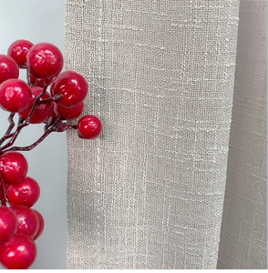 Nahaufnahme von hellbeige Leinenvorhangstoff mit grober Textur und roten Beeren