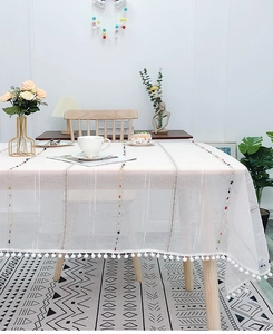Detail of Nordic cotton linen tablecloth featuring rainbow dots and white pom-pom fringe