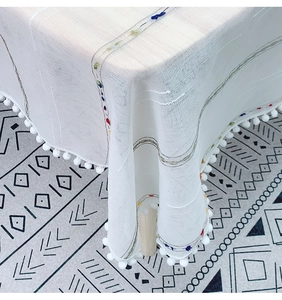 Detail of white linen tablecloth with rainbow stripes and pom-pom fringe edges