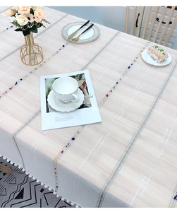 Close-up of Nordic linen tablecloth with colorful tassels and white pom-pom fringe detail