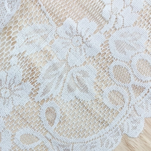 Nordic white lace curtain with floral embroidery and scalloped edges on wooden background