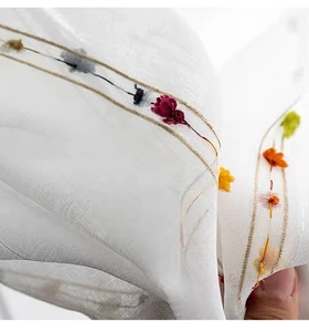 Close-up of white translucent table runner with colorful embroidery and gold stripes