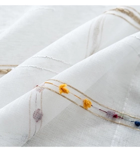 Macro shot of white sheer tablecloth with colorful 3D floral accents and fine texture