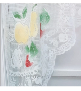 Detail of white lace kitchen curtain with colorful strawberry print and wavy edge