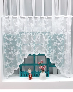 Detail of white lace cafe curtain with rose embroidery and scalloped edge on wooden window