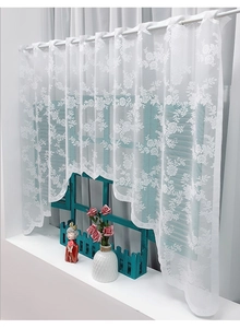 Detail of white lace coffee curtain with floral embroidery and scalloped bottom edge