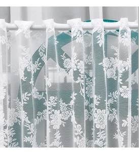 Detail of white lace cafe curtain with delicate floral embroidery and tab top design