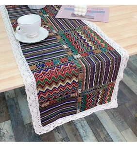 Close-up of bohemian geometric table runner featuring white lace trim on wooden desk