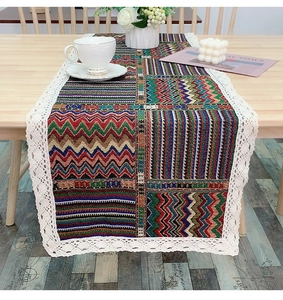 Close-up of bohemian table runner with colorful patterns and white lace edges on wood table