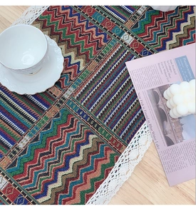 Detailed view of woven table runner with colorful ethnic patterns and white lace edges