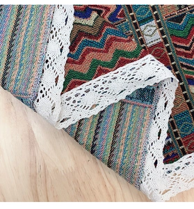 Detailed view of bohemian geometric woven fabric with white lace edge on wood