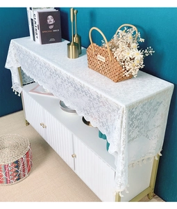 Detail of white lace table runner with floral embroidery and bohemian tassel fringe