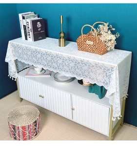 Close-up of white floral lace runner with elegant tassel fringe on a modern console cabinet