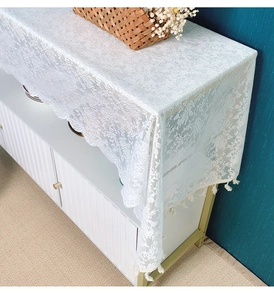 Detail view of white lace table runner with floral crochet patterns and fringe tassels